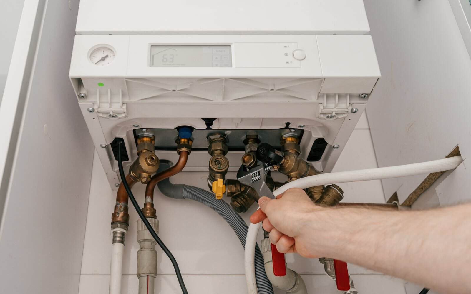 Engineer installing connections beneath a domestic boiler in Reigate