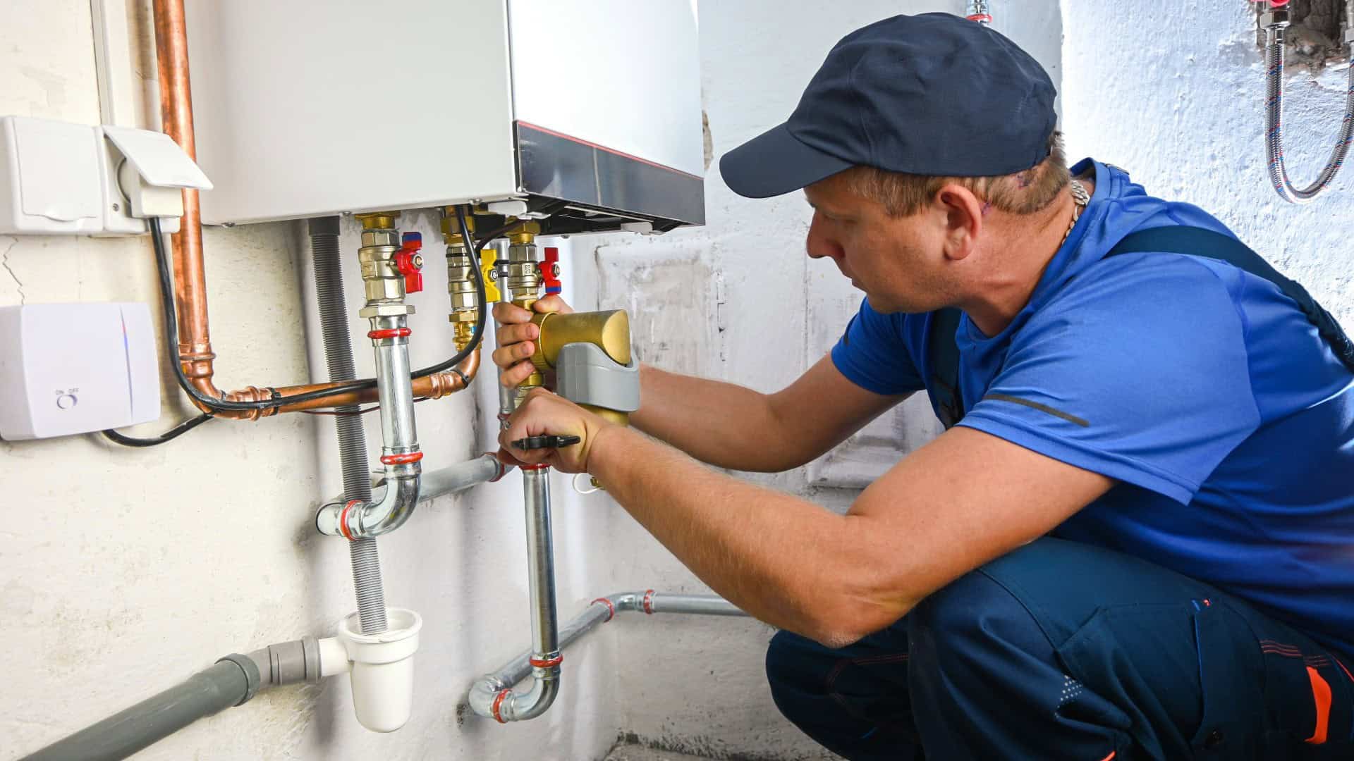 Gas engineer working on pipework beneath a domestic boiler